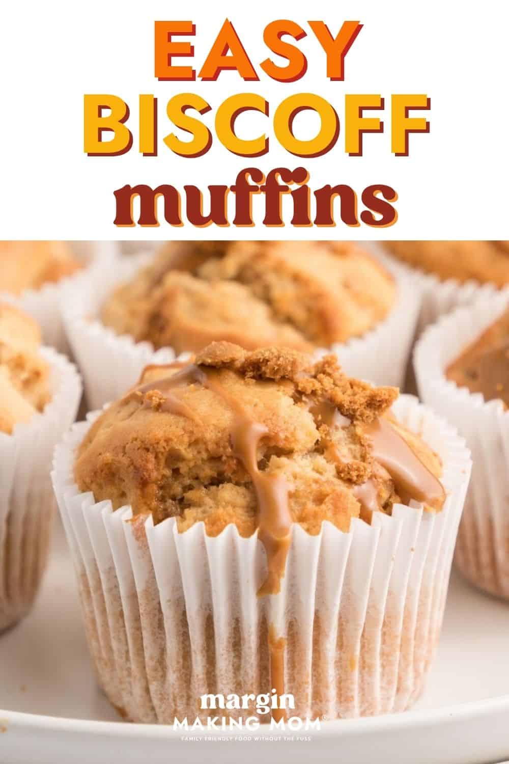 Biscoff muffin in a white paper liner, topped with a cookie butter drizzle and crushed cookie pieces.