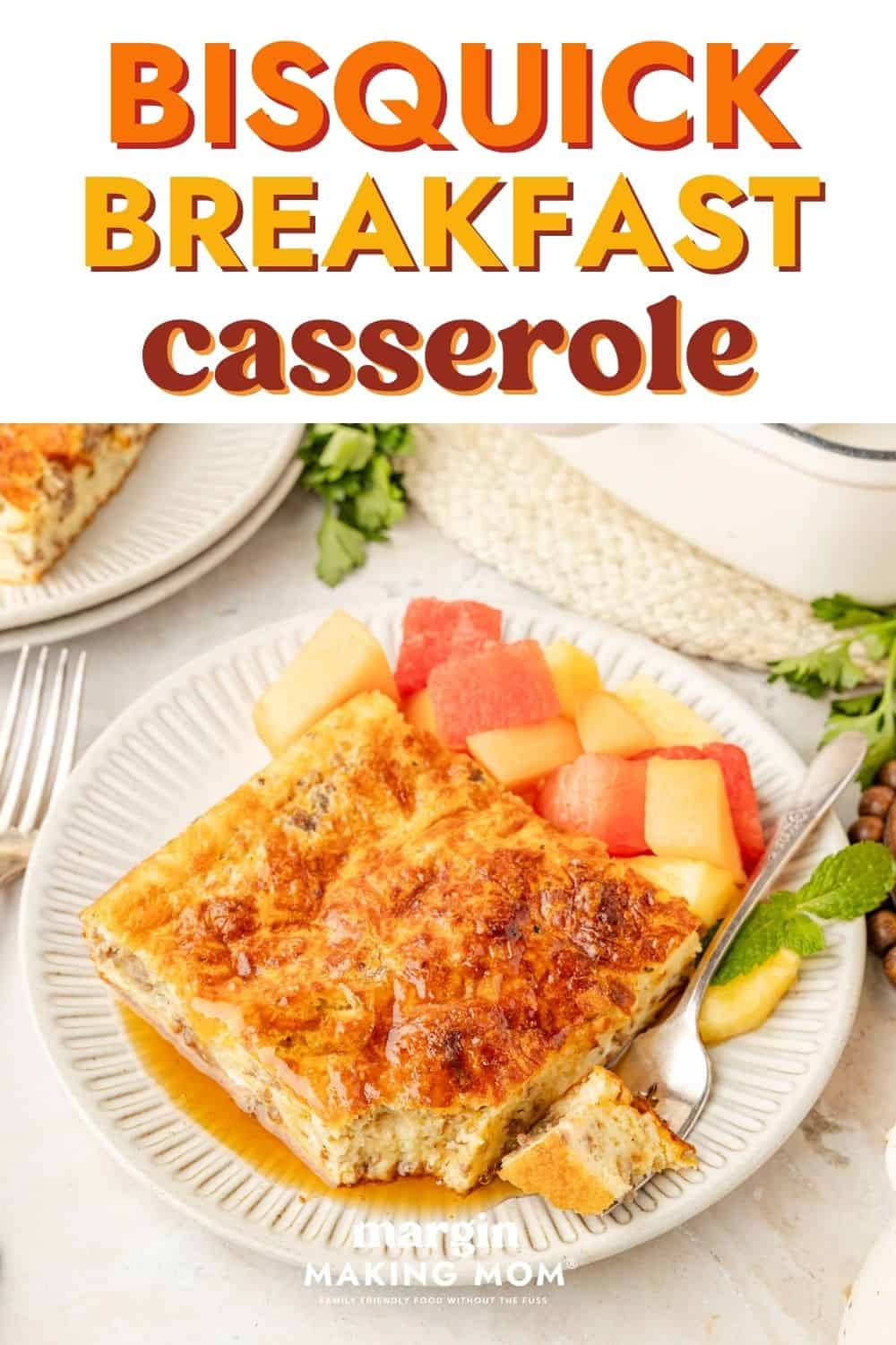 Slice of easy Bisquick breakfast casserole served on a white plate with fresh fruit.