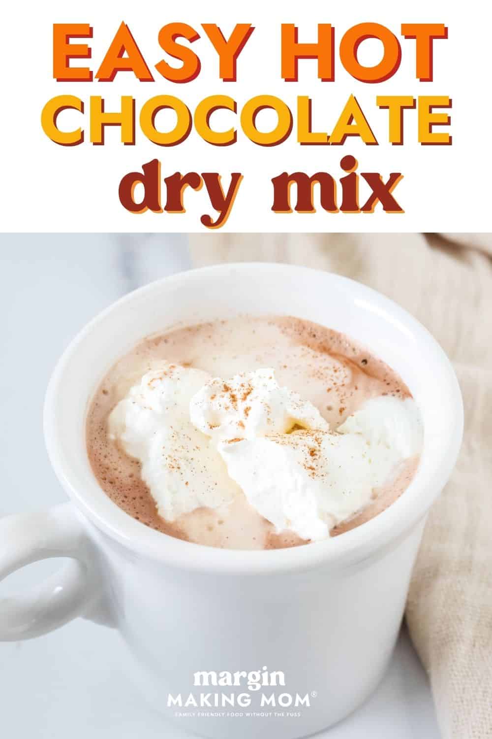 Mug of cocoa made with easy hot chocolate dry mix. The cocoa is topped with whipped cream and a sprinkling of cinnamon.