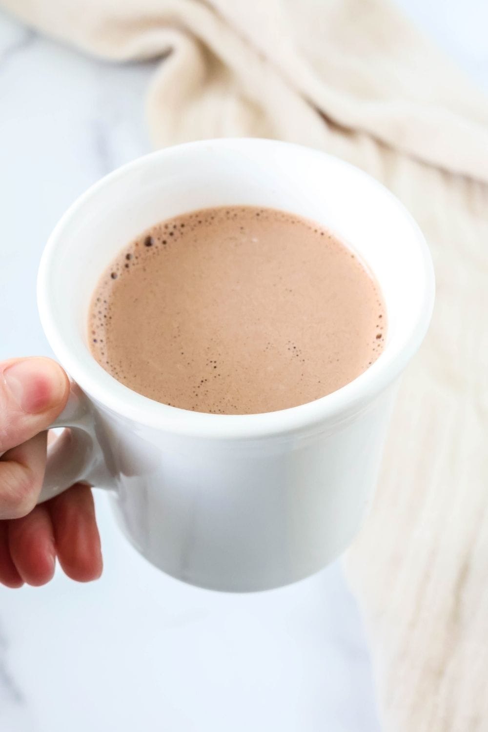 A hand holds a cup of fat free hot chocolate.