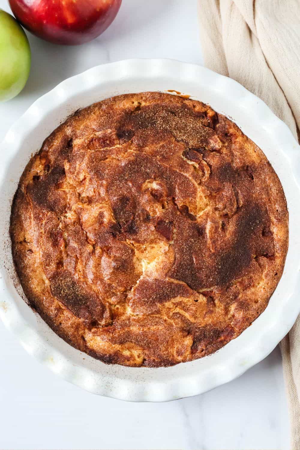 Overhead view of a fresh apple cake baked in a stoneware pie pan.