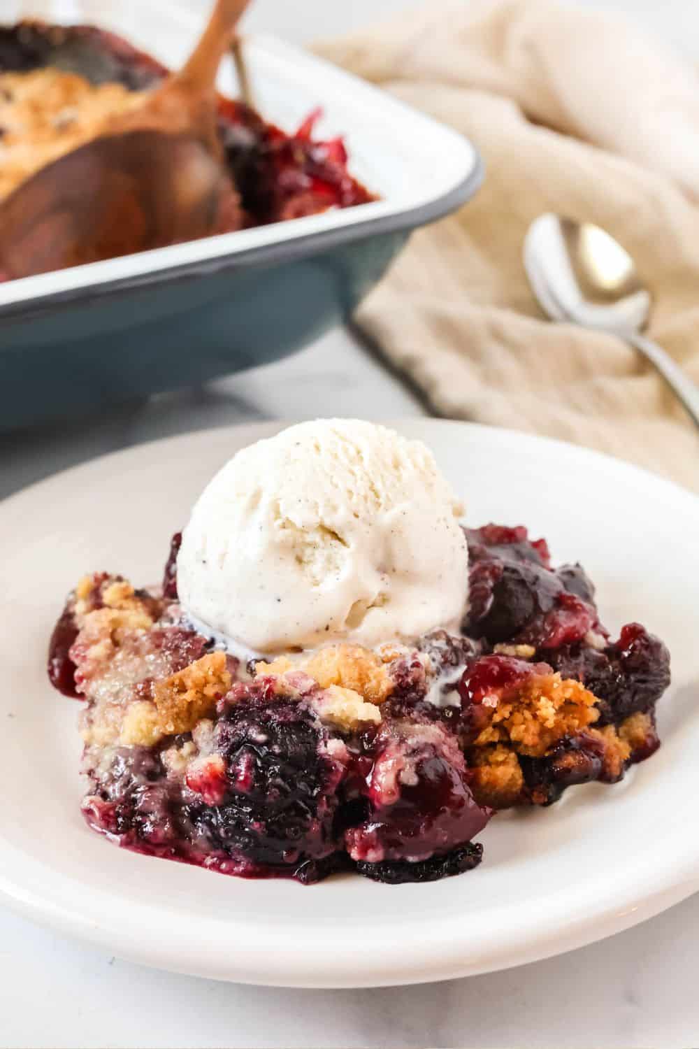 Frozen cherry cobbler on a white plate with a scoop of vnailla ice cream.