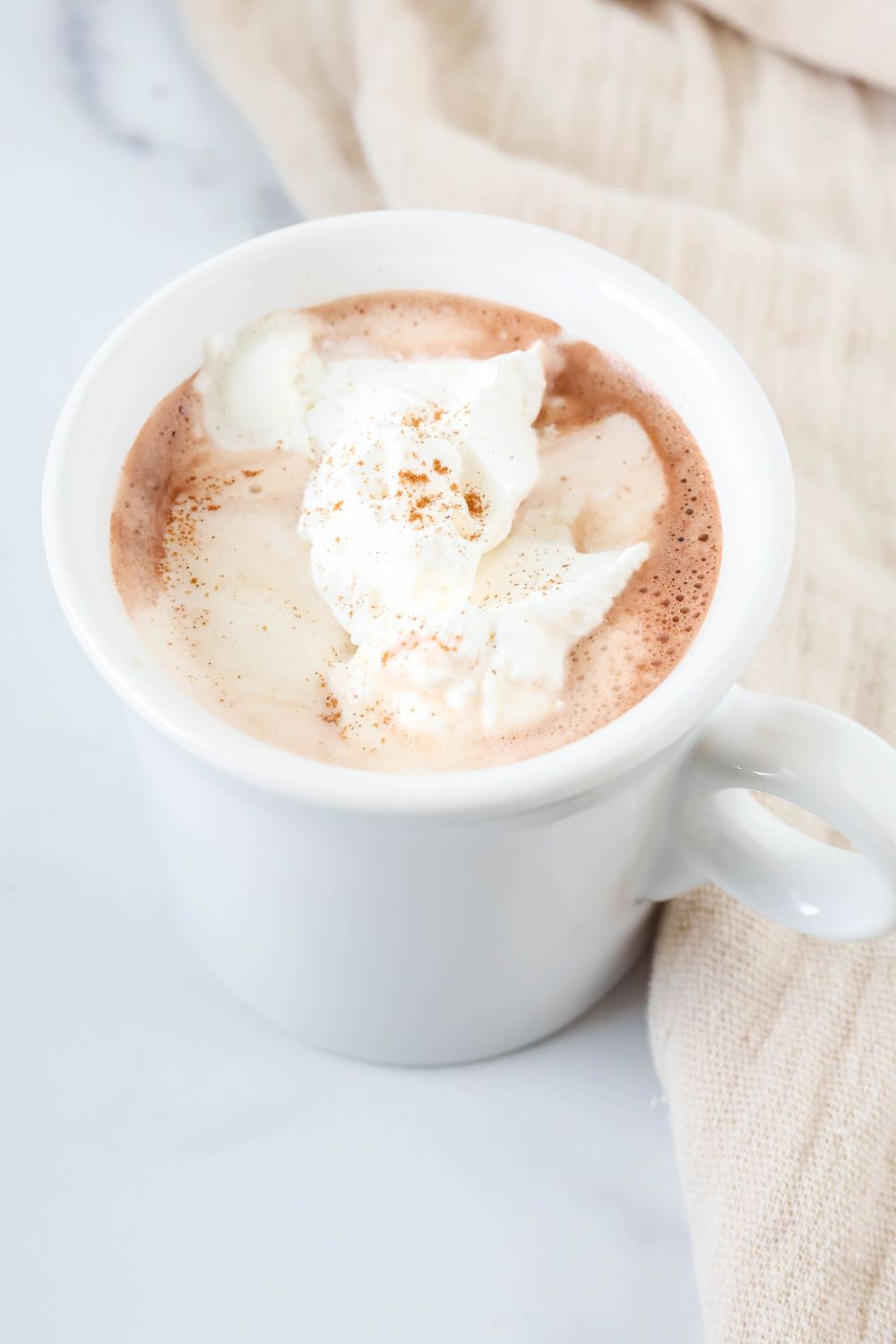 white mug with fat free hot cocoa in it, topped with reduced-fat cool whip.