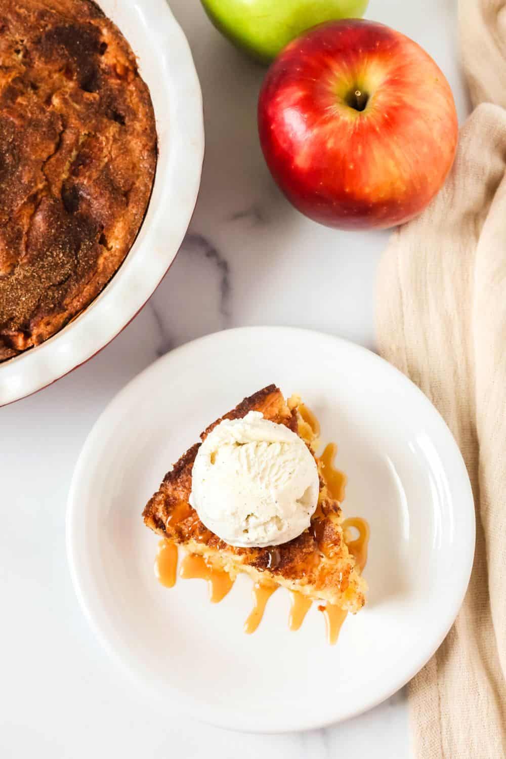 Overhead view of a slice of old-fashioned apple cake, drizzled with caramel sauce and topped with a scoop of ice cream.
