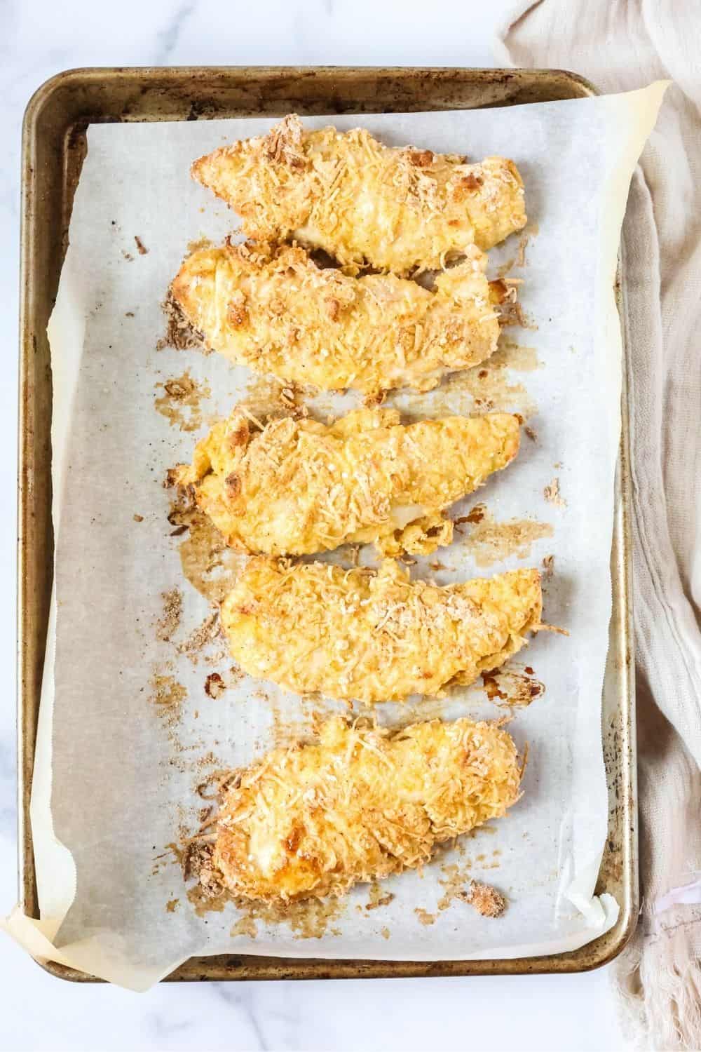 Overhead view of a baking sheet with oven-baked chicken tenders coated with Bisquick