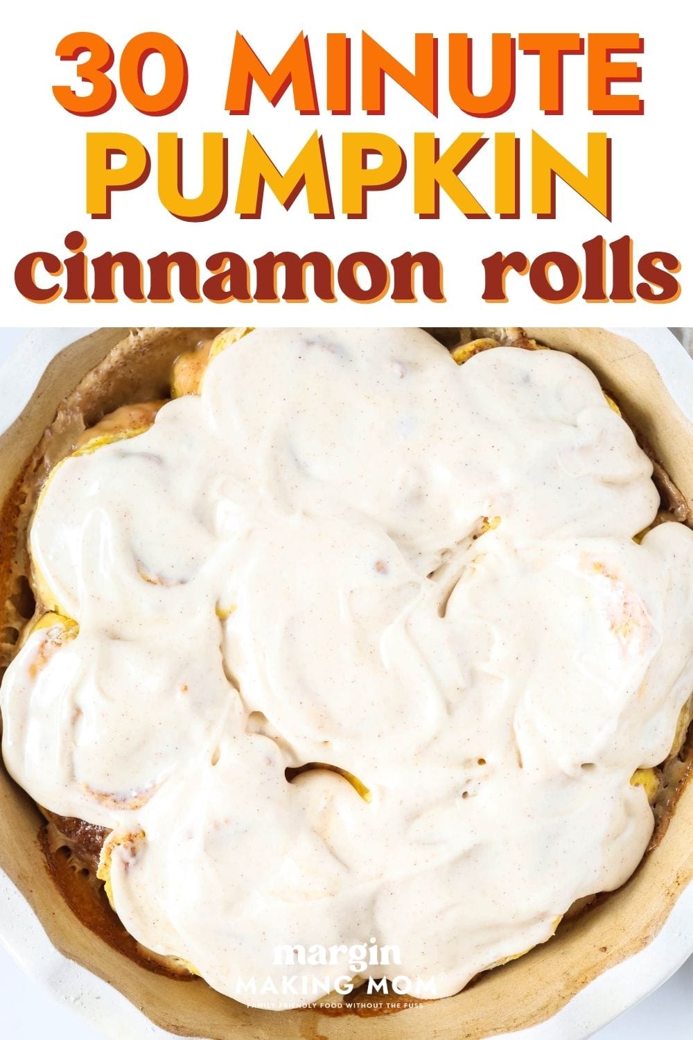 Overhead view of a round pan of 30-minute pumpkin cinnamon rolls covered with icing.