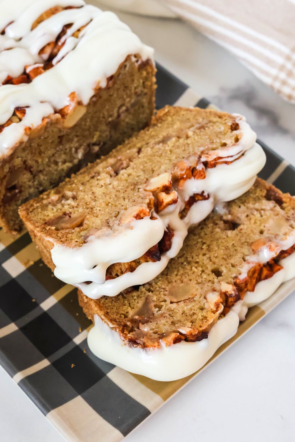 Partially slice loaf of Amish apple fritter bread topped with glaze.