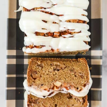 Overhead view of a loaf of apple fritter bread with two slices cut out of it, showcasing the tender crumb and chunks of apples in the bread, as well as the icing glaze on top.