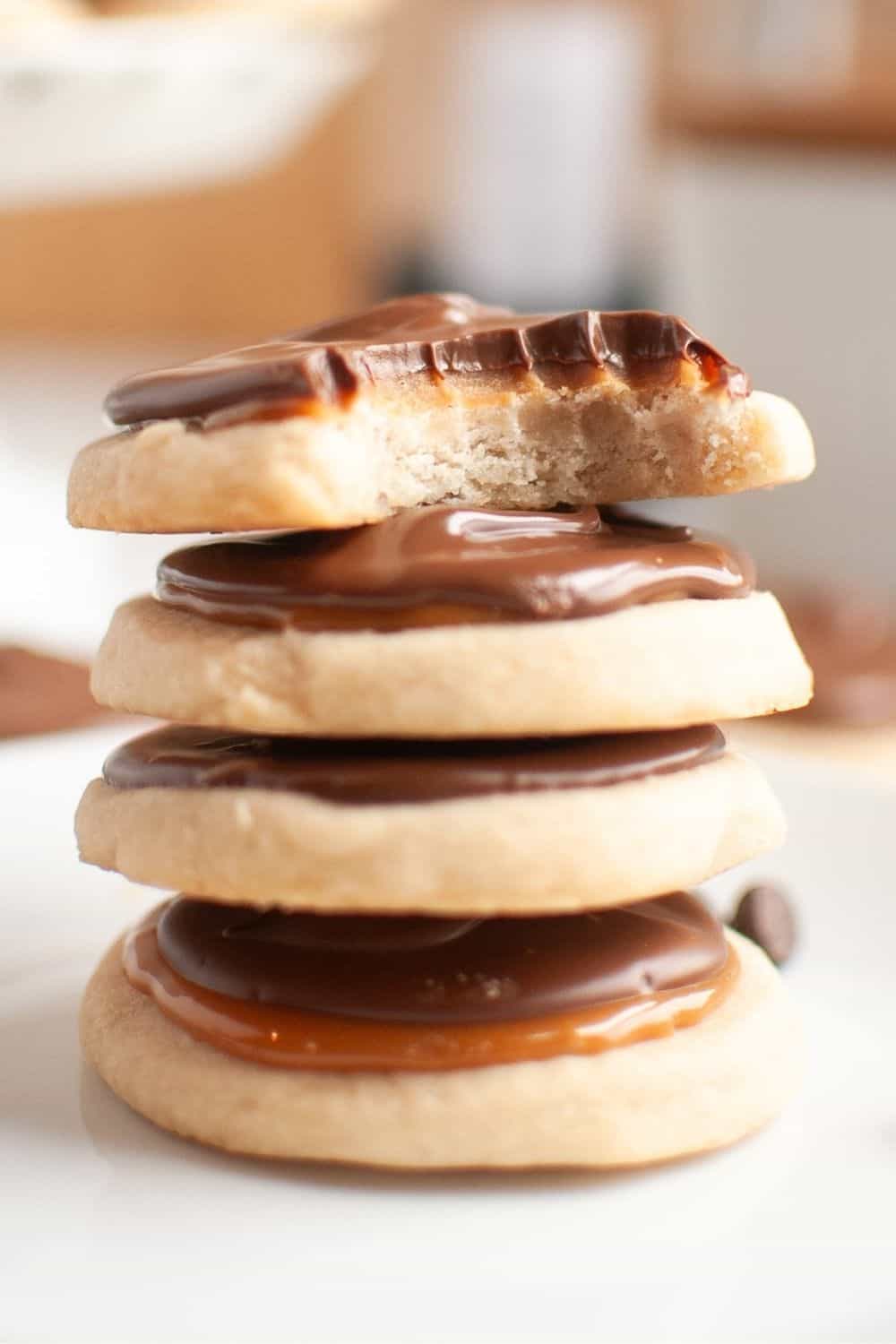 Stack of Twix cookies, similar to Crumbl cookies. The top cookie has a bite taken out of it.