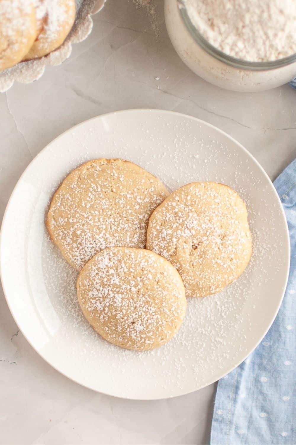 Cream cheese pound cake cookies dusted with powdered sugar and served on a white plate.