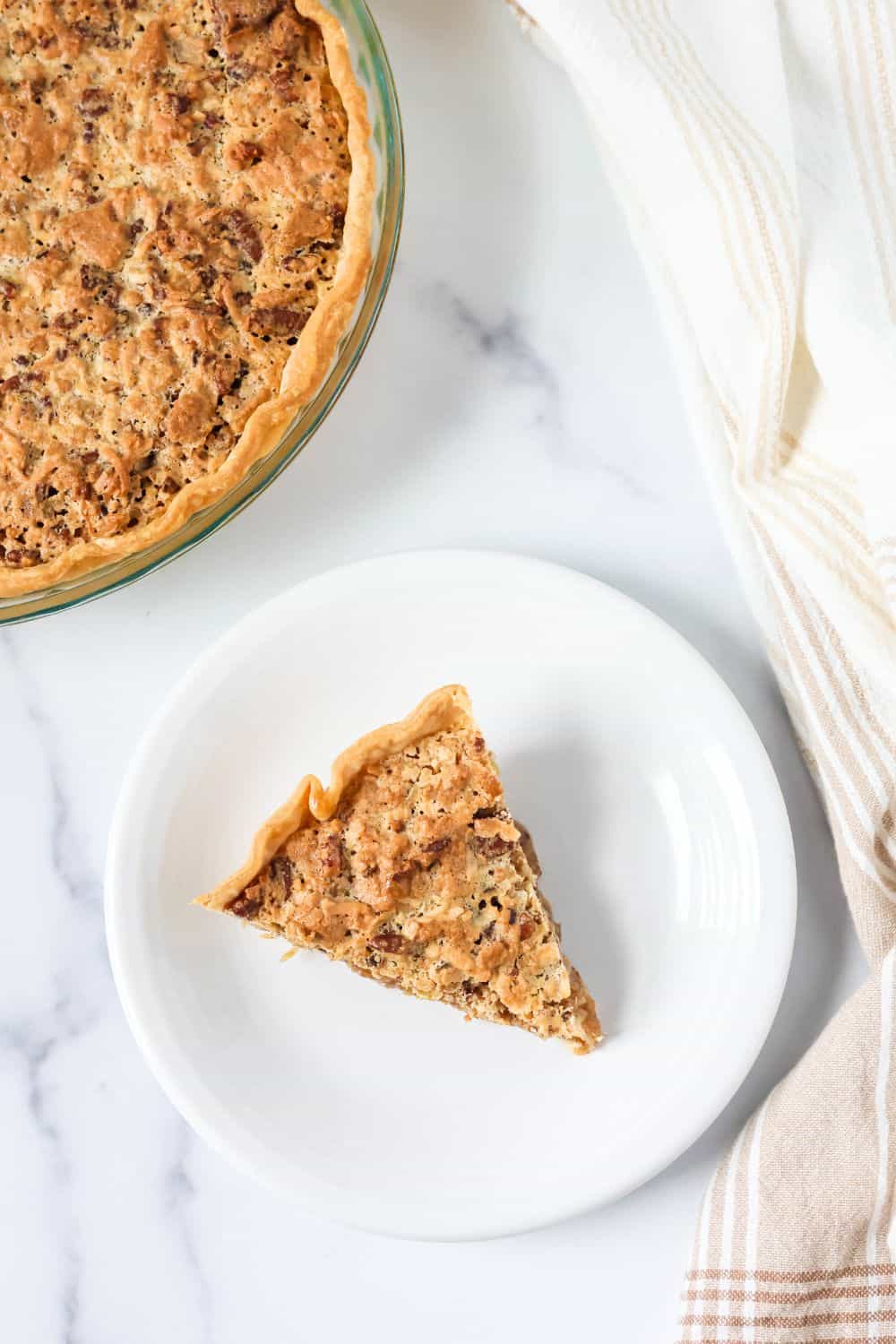 Overhead view of a slice of sawdust pie on a white dessert plate, with the whole pie next to it.