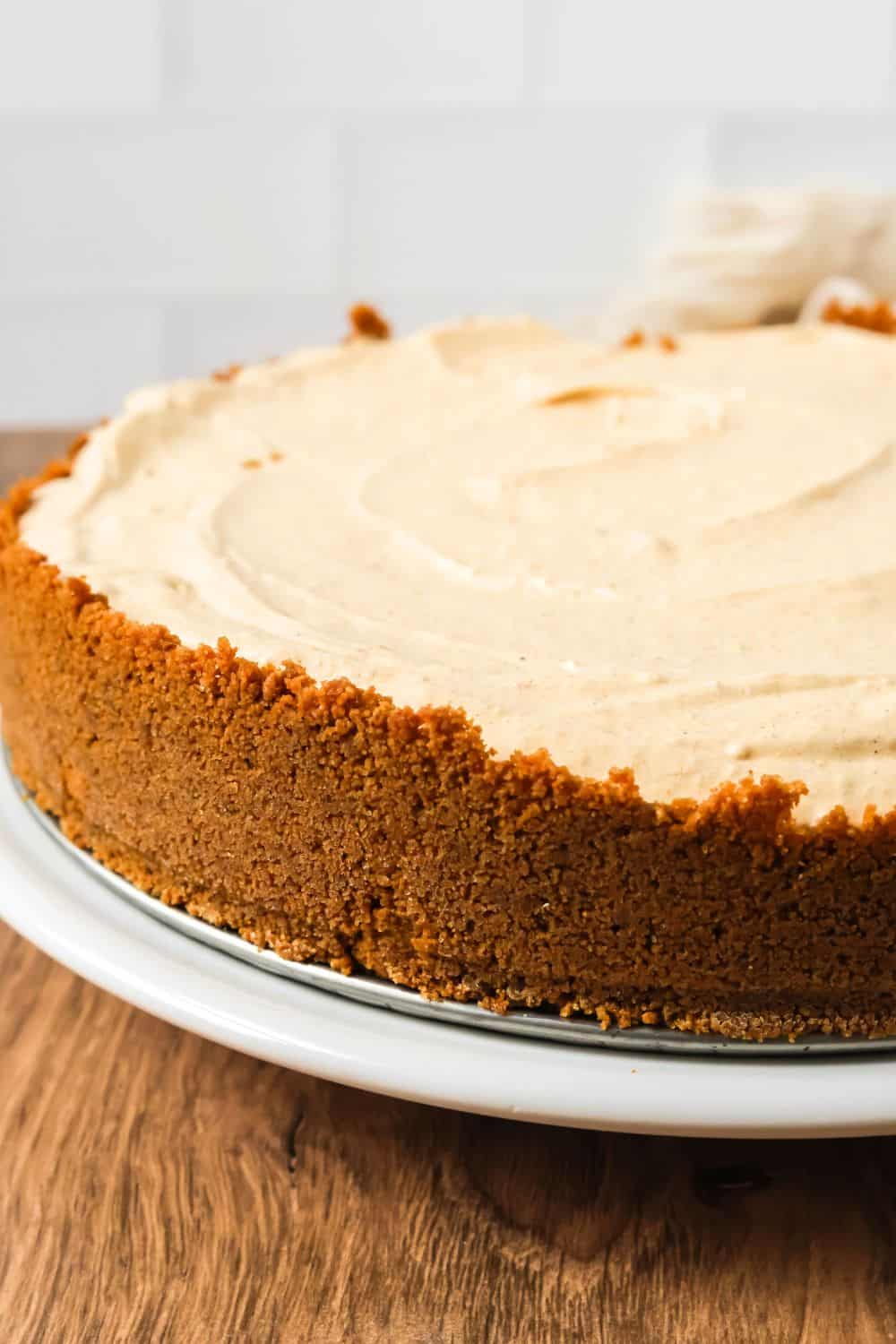 Side view of a frozen pumpkin pie cheesecake, showing the detail of the Biscoff crust.