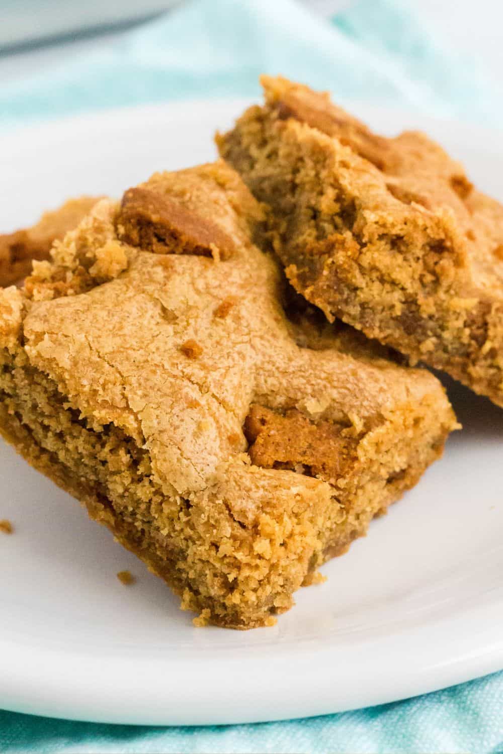 close-up view of Lotus Biscoff blondies on a white plate, showing the soft and chewy interior and the pieces of cookies on top.