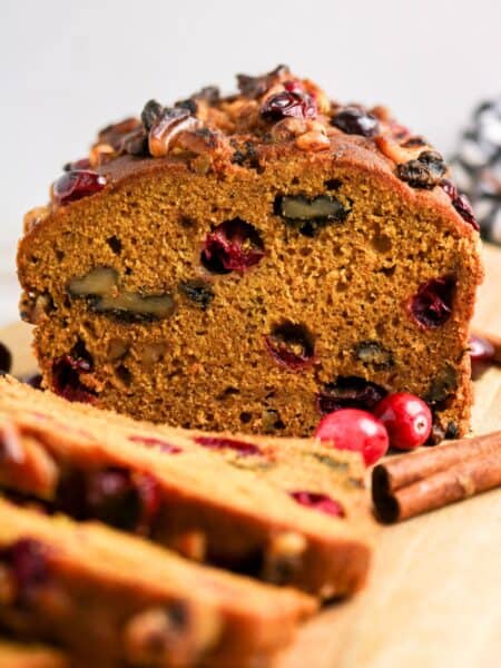 Pumpkin cranberry bread loaf, partially sliced.