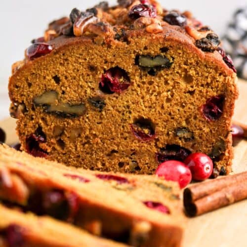 Pumpkin cranberry bread loaf, partially sliced.