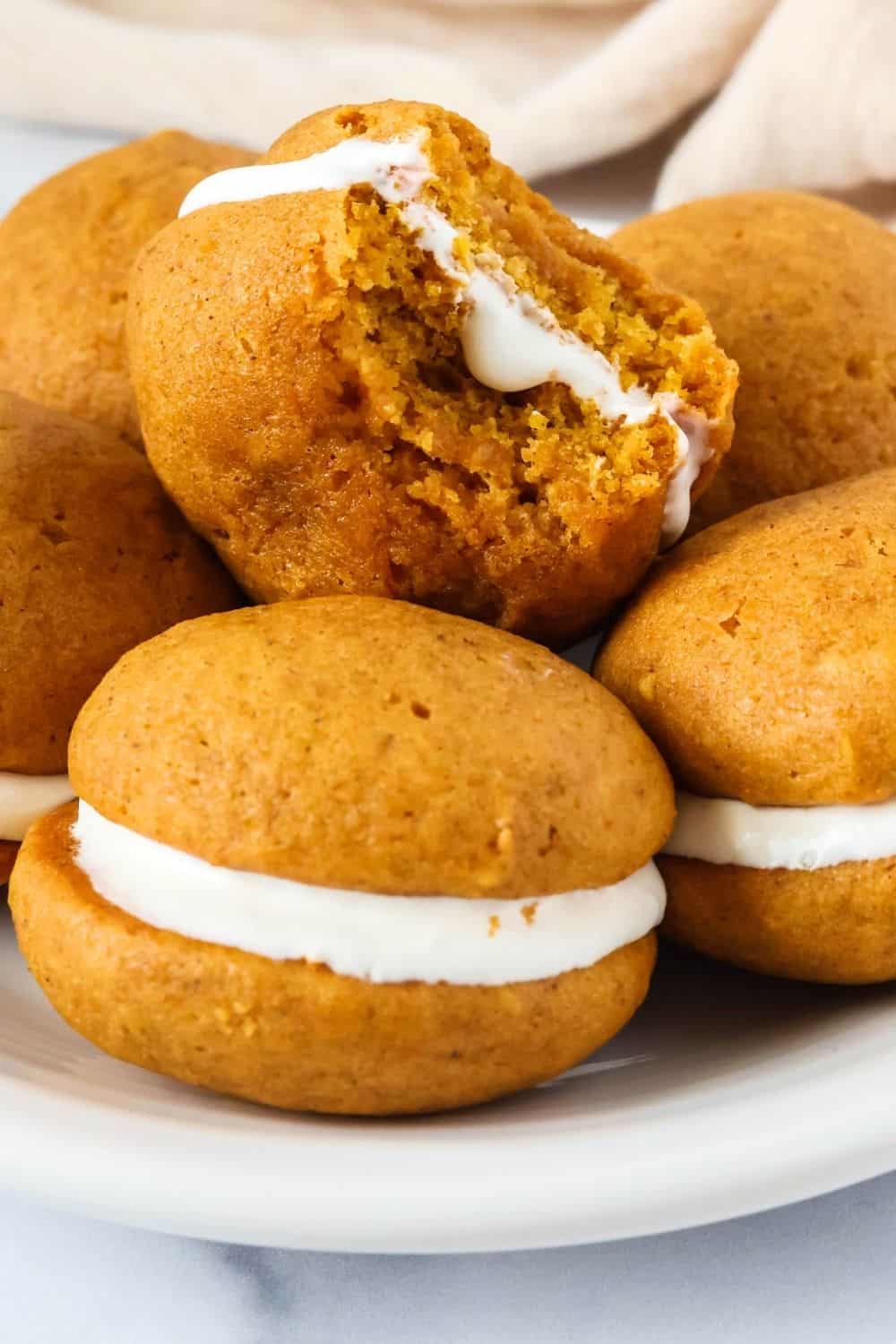Side view of pumpkin sandwich cookies with marshmallow fluff cream cheese filling.