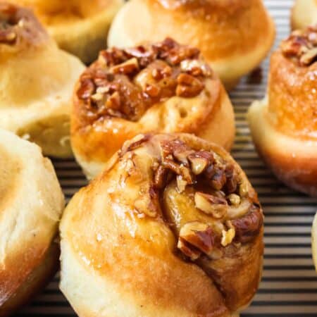 Schnecken sweet rolls topped with pecan and brown sugar mixture, served on a striped platter.