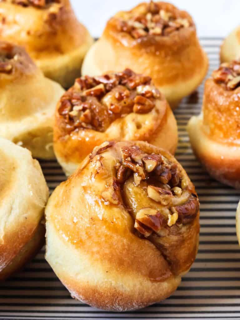 Schnecken sweet rolls topped with pecan and brown sugar mixture, served on a striped platter.