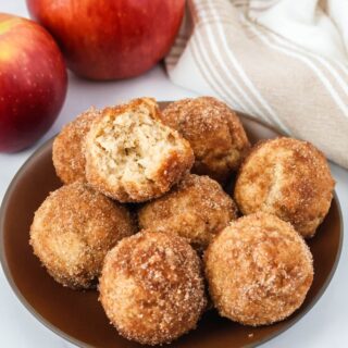 Bisquick apple cider donut holes served on a brown plate. One of the doughnut holes has a bite taken out of it.
