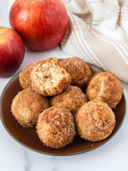 Bisquick apple cider donut holes served on a brown plate. One of the doughnut holes has a bite taken out of it.