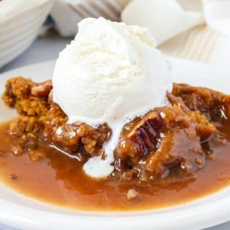 Bisquick pumpkin cobbler served on a white plate, topped with a scoop of vanilla ice cream.