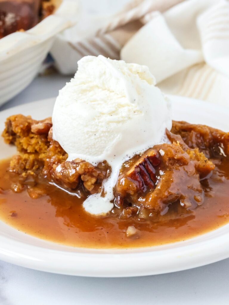 Bisquick pumpkin cobbler served on a white plate, topped with a scoop of vanilla ice cream.