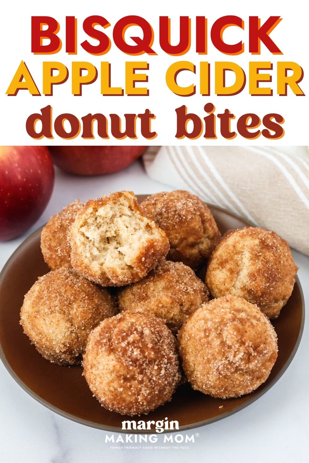 Apple cider doughnut holes served on a brown plate. The baked donut holes are coated in cinnamon sugar, and one has a bite taken out of it to show its moist interior.