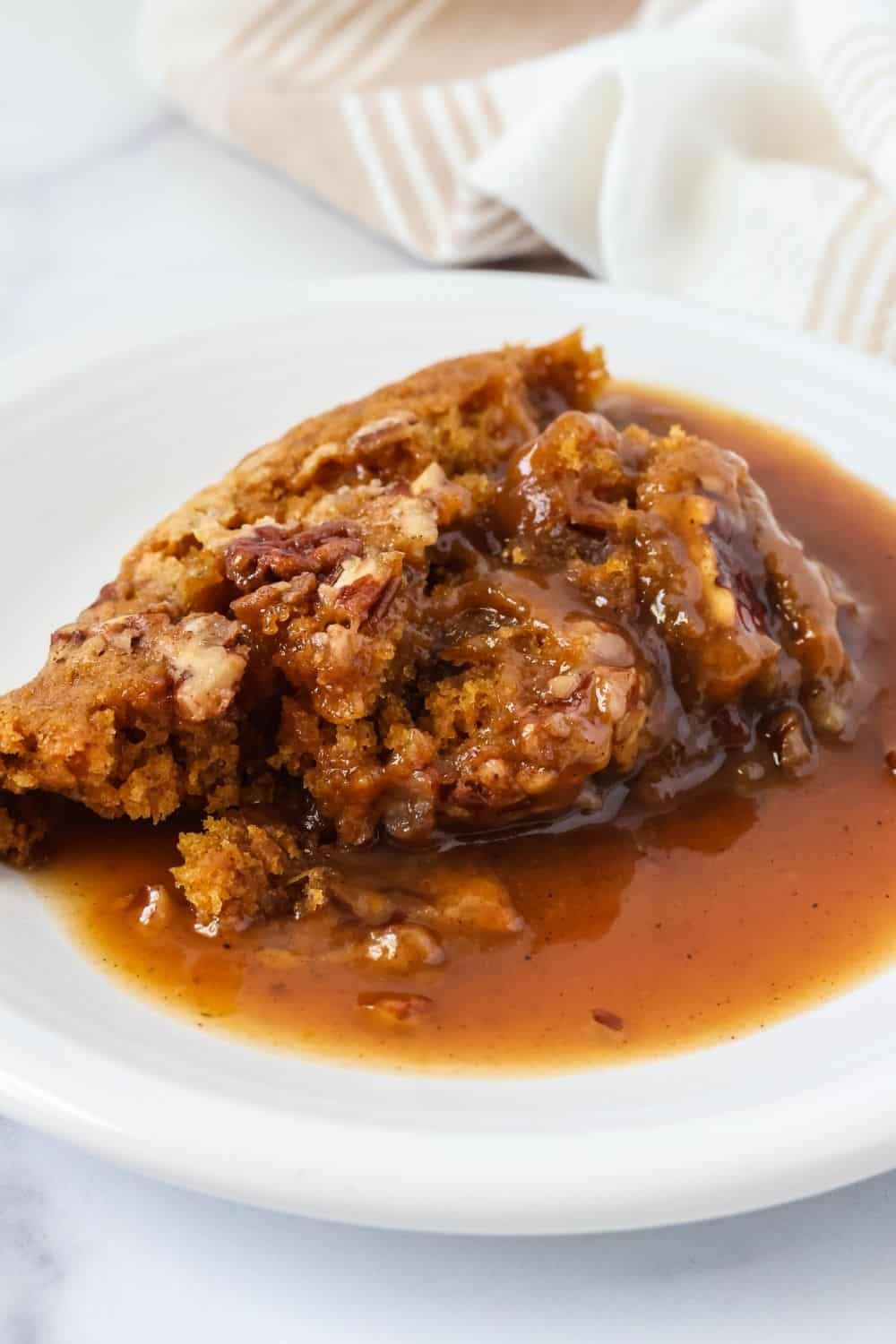 A scoop of Bisquick pumpkin cobbler with its sweet caramel-like sauce, served on a white plate.