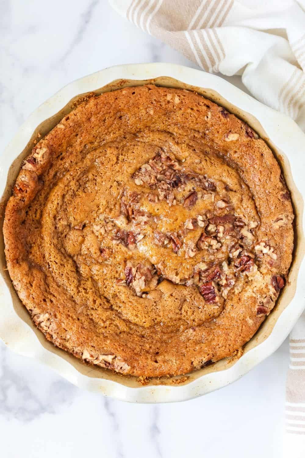Overhead view of a deep dish pie pan of freshly baked pumpkin cobbler made without a cake mix.
