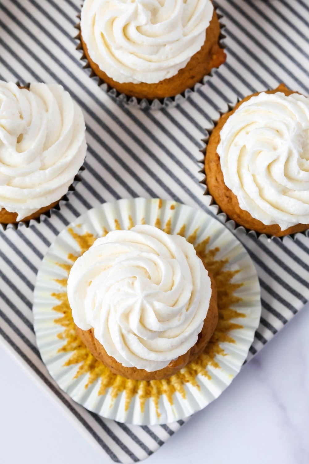 Overhead view of pumpkin spice cupcakes topped with swirls of boiled milk frosting.
