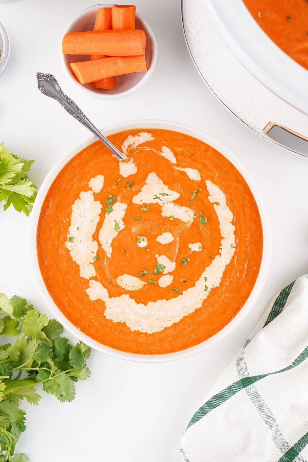 Overhead view of a bowl of vegetarian carrot soup drizzled with cream.