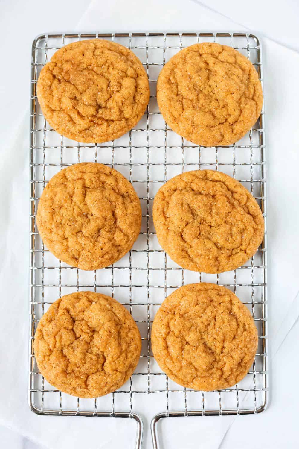 Overhead view of six pumpkin and molasses cookies on a wire rack.