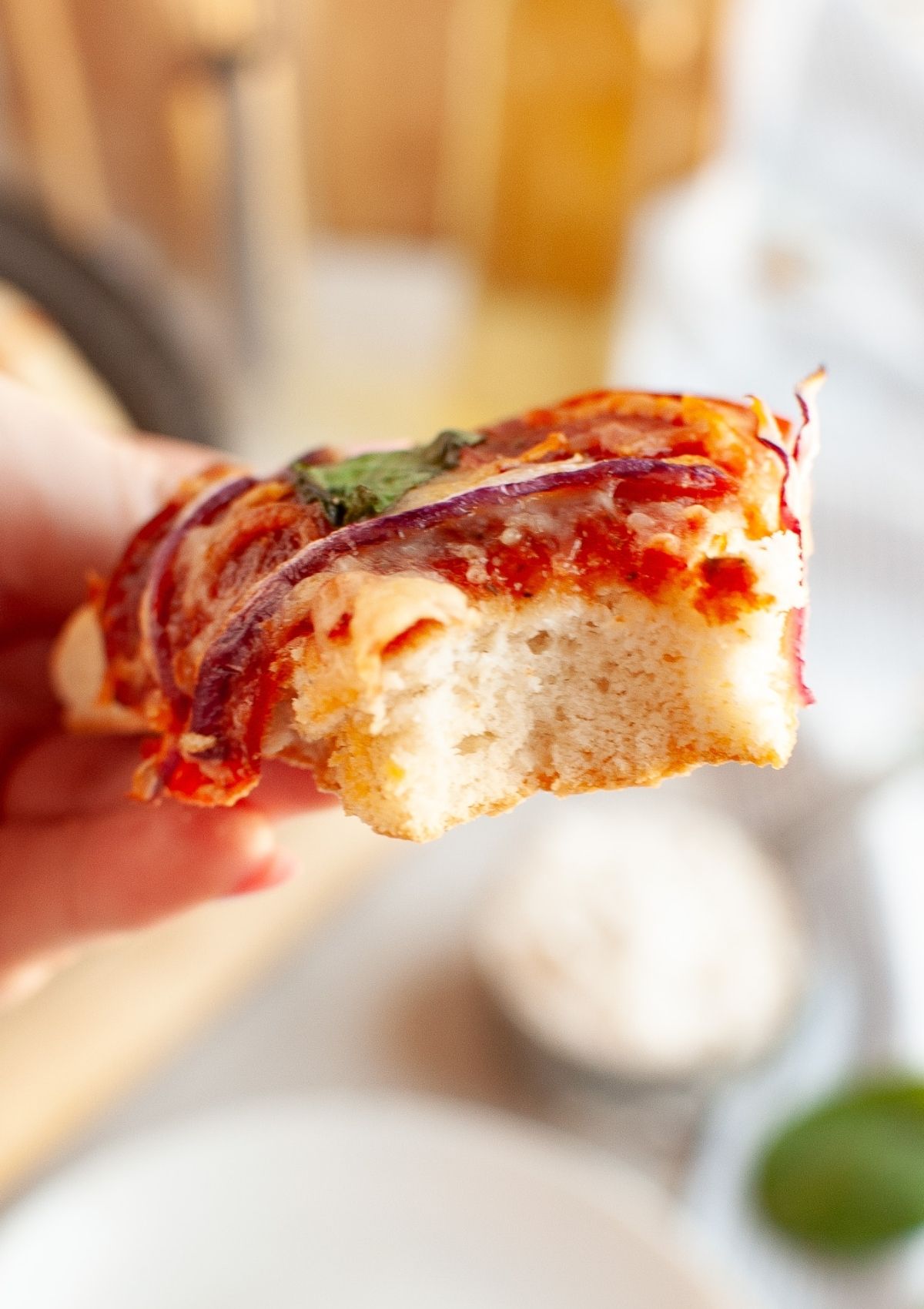 Slice of pizza made with Bisquick pizza dough, with a bite taken out of the slice to showcase the soft interior.