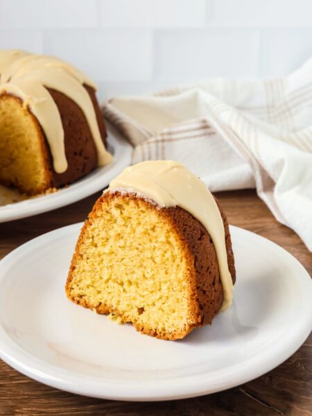 Slice of brown sugar pound cake from a mix, topped with brown sugar icing, served on a white plate.