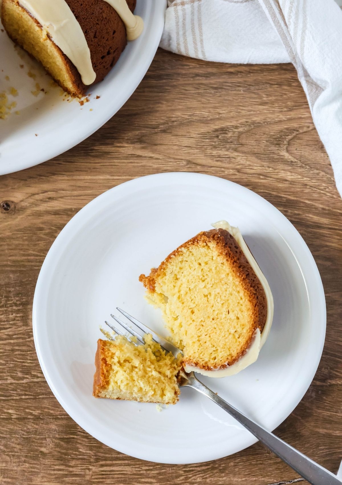 Overhead view of a slice of cake mix brown sugar pound cake on a white plate. A fork has cut a bite out of the slice.