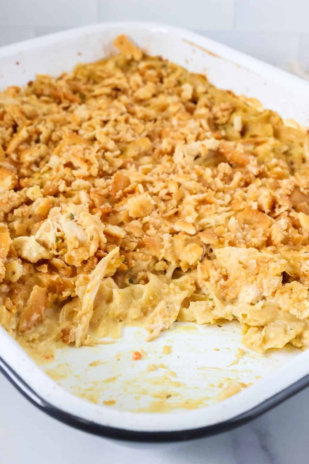 Chicken and noodle casserole topped with ritz crackers, in a baking dish. Some of the noodles have been scooped out of the dish.