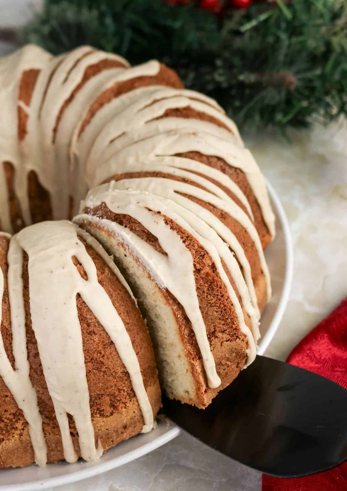 side view of an eggnog pound cake. A cake server is lifting a slice from the bundt cake.