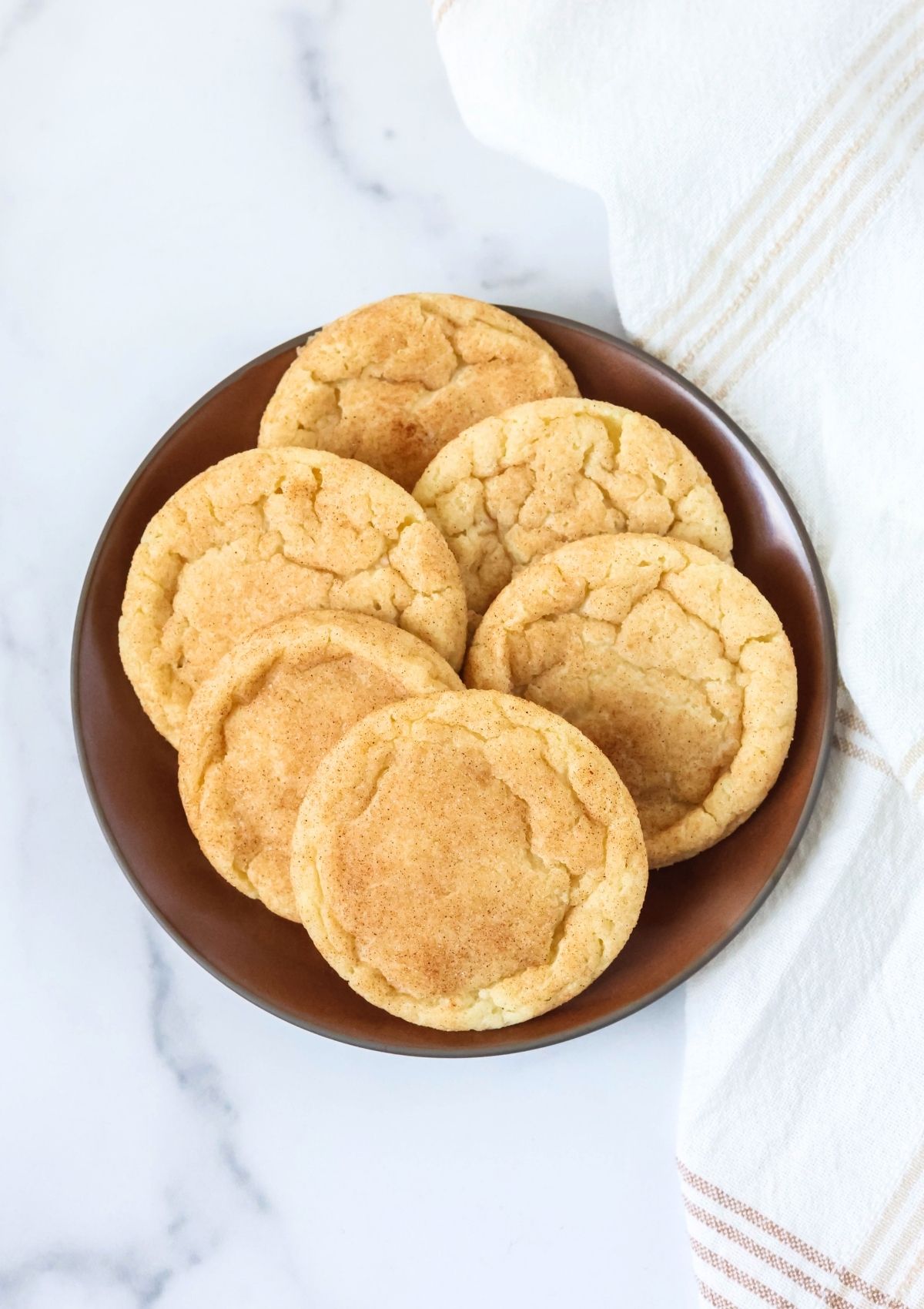 Overhead view of a brown plate with several dairy-free snickerdoodle cookies on it.