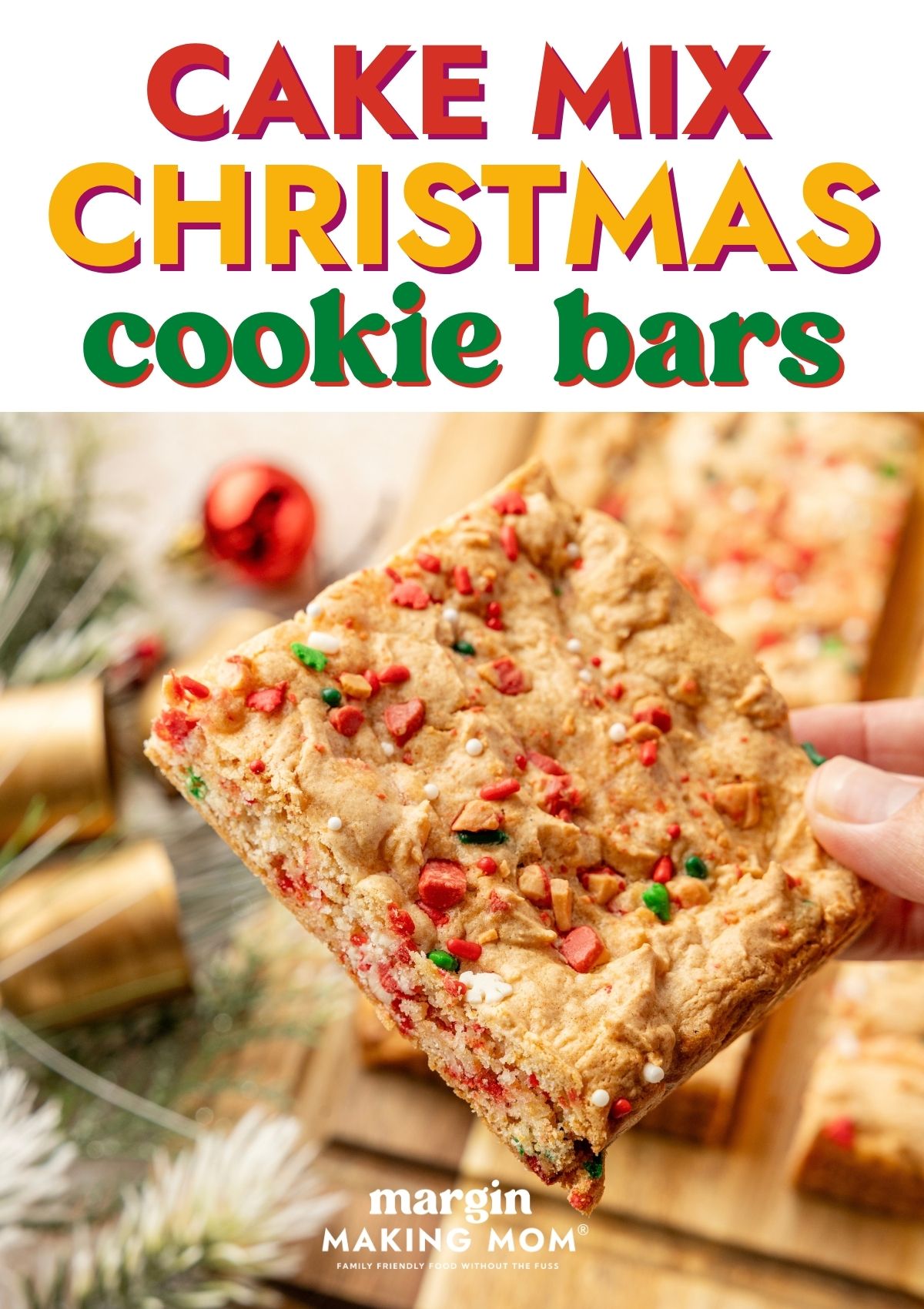 A hand holds a cake mix Christmas cookie bar, showcasing the sprinkles and peppermint baking chips throughout the chewy bar.