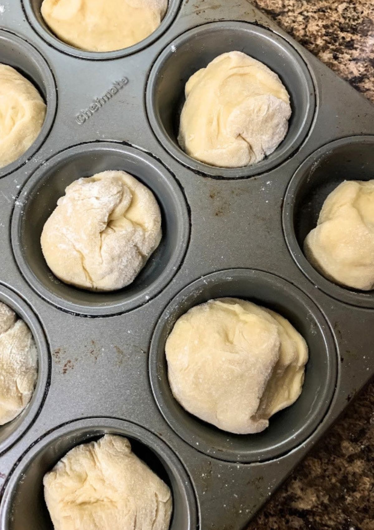 Frozen dinner roll dough in a muffin pan.