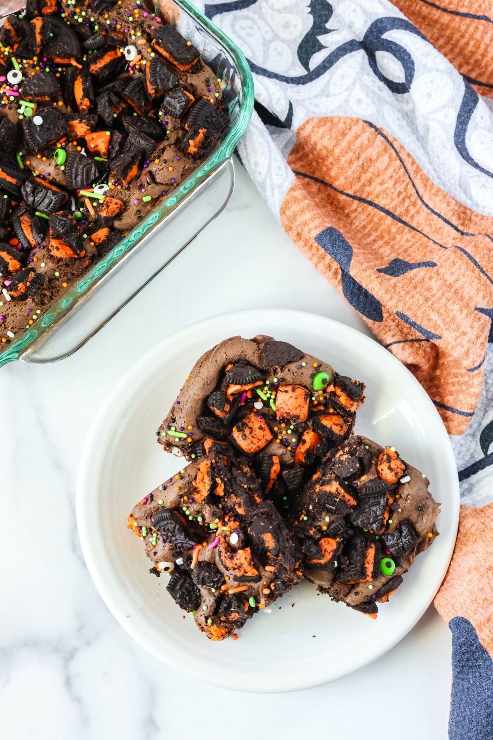 Overhead view of a white plate with three Halloween cookie bars made with a cake mix. The pan of remaining bars is next to the plate.
