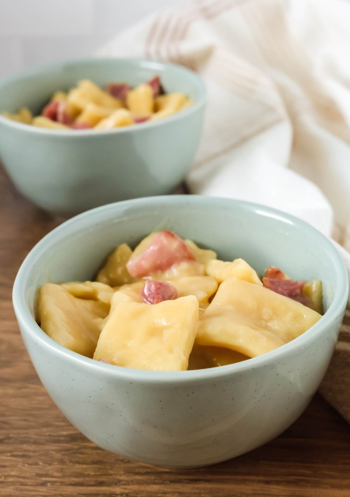 Two light blue bowls filled with ham and slicks dumplings.