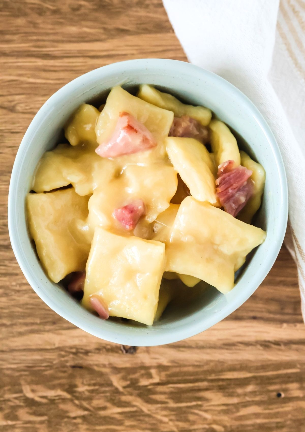 Overhead view of homemade ham and dumplings served in a light blue bowl.