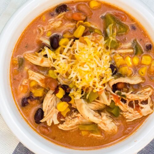 Instant Pot chicken taco soup served in a white bowl and garnished with shredded cheese.
