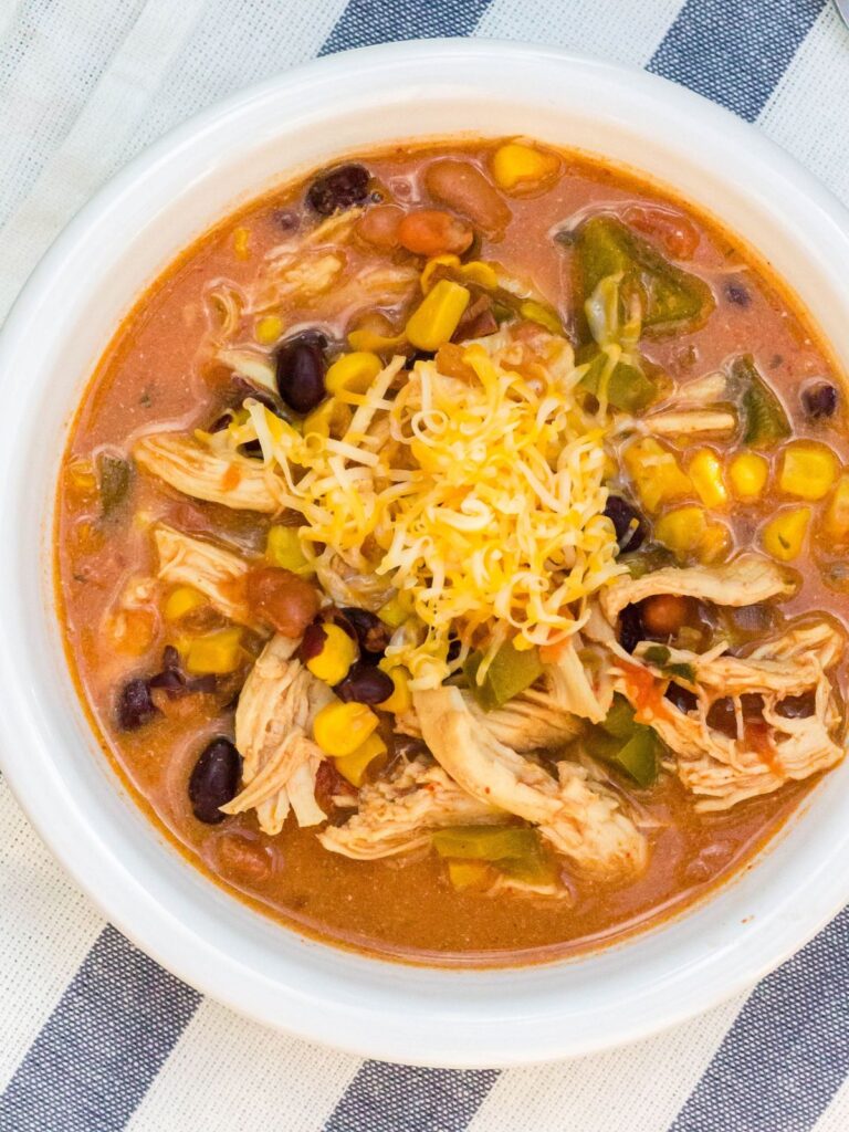 Instant Pot chicken taco soup served in a white bowl and garnished with shredded cheese.