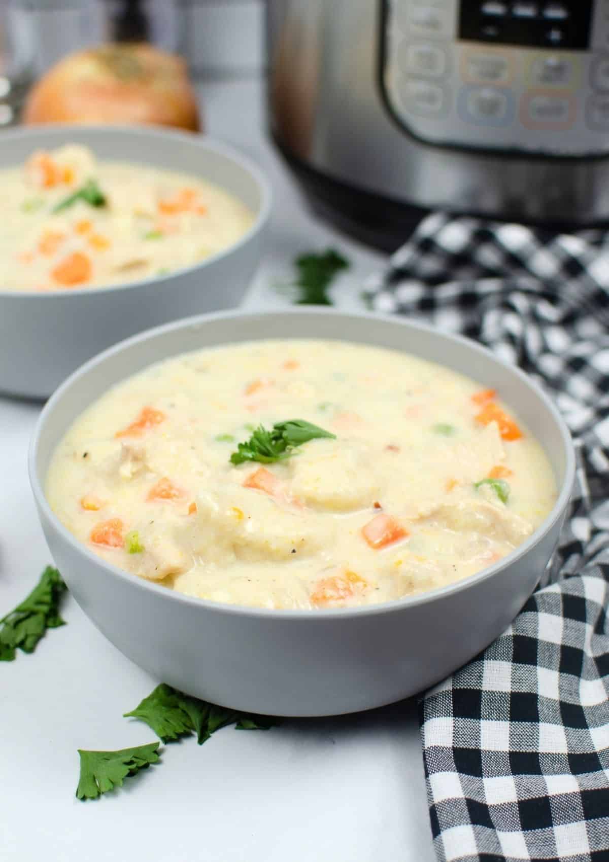 two bowls of chicken and dumplings made with Grands biscuits, sitting on a counter in front of an Instant Pot pressure cooker