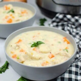 two bowls of Instant Pot chicken and dumplings made with biscuits, placed in front of an Instant Pot pressure cooker