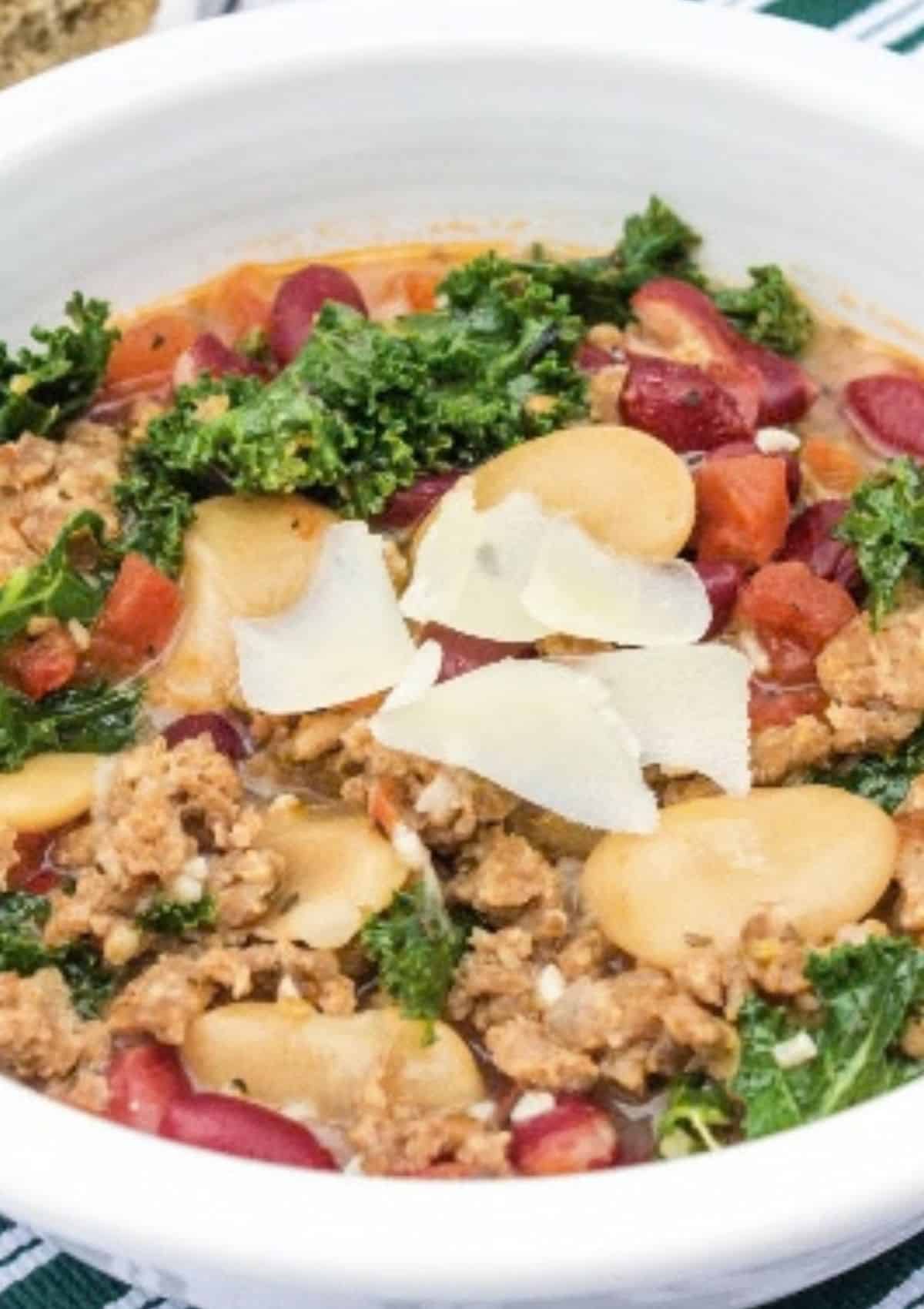 Close-up view of a white bowl filled with rustic italian sausage bean soup.