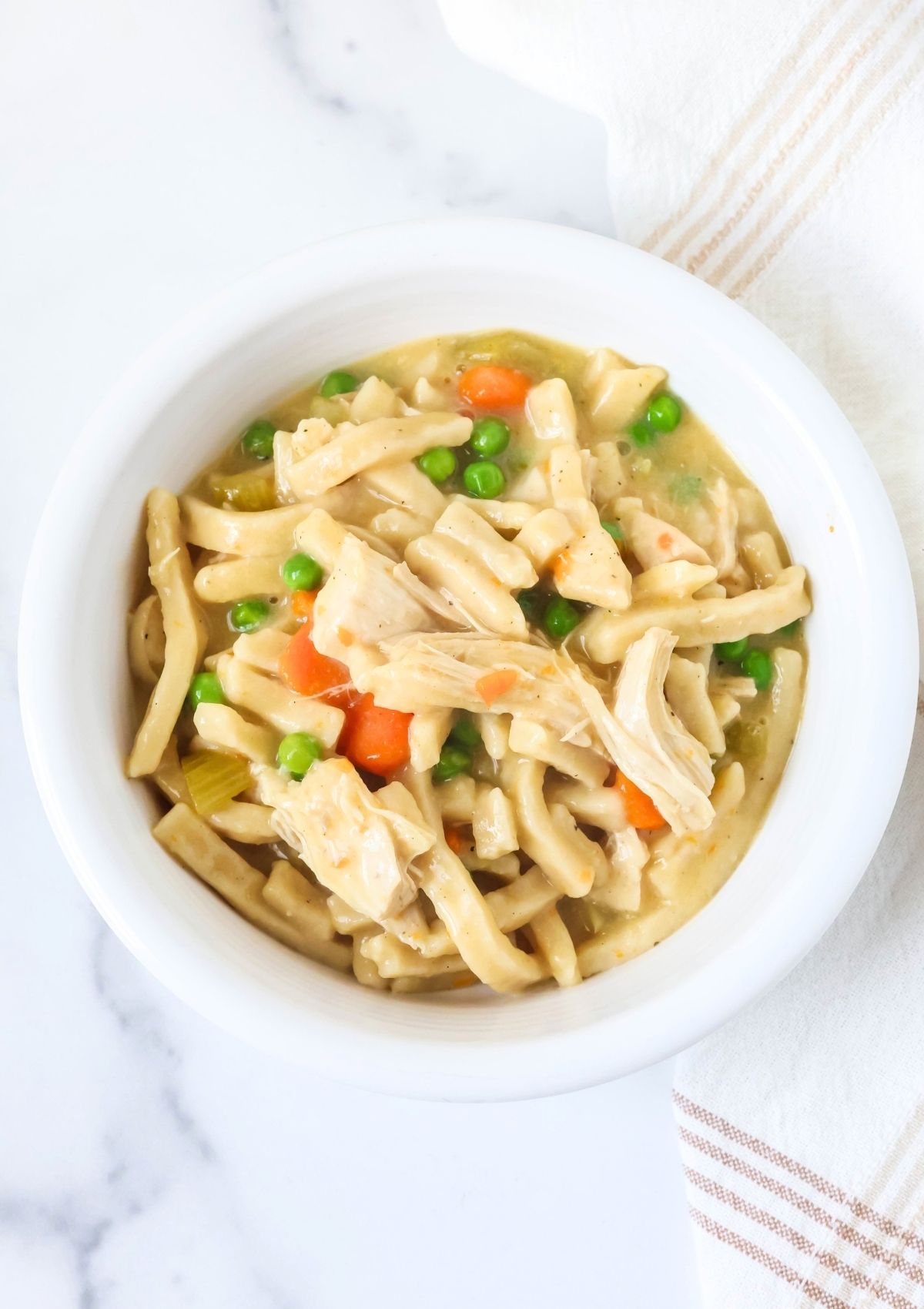 Overhead view of a white bowl filled with chicken and dumplings with noodles that was cooked in the Instant Pot.