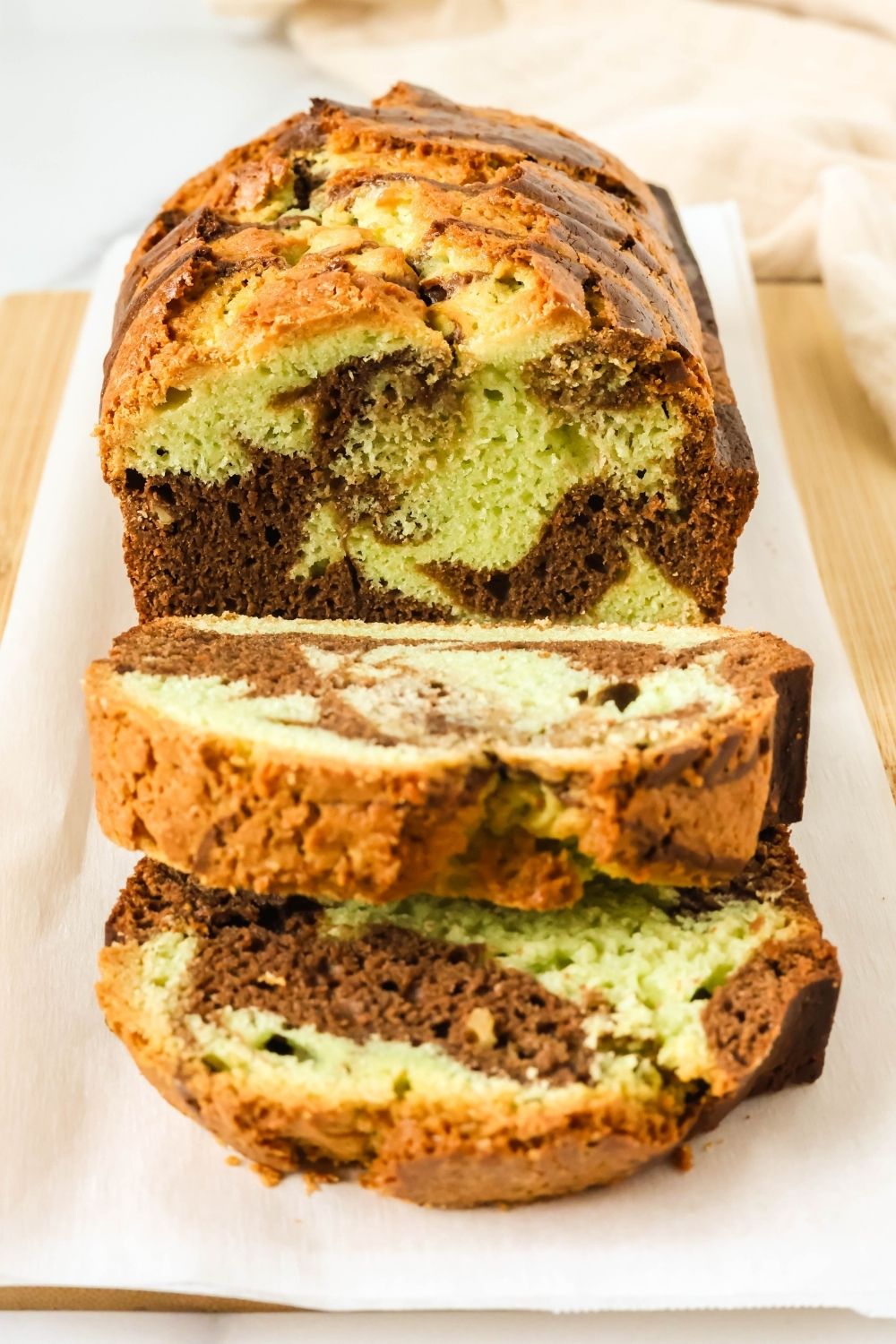 Loaf of marbled chocolate pistachio bread that's partially sliced.